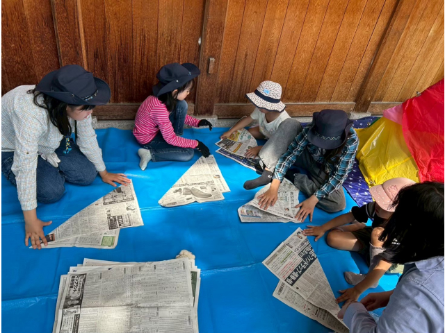 新聞紙を半分に裂いて15㎝程の大きさに丸めますスカウトが体験に参加した子にやり方を教えます