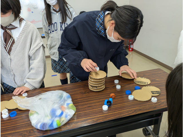 ペットボトルのフタと段ボールを交互に積みます。どれだけ高く積み上げられるか競争です